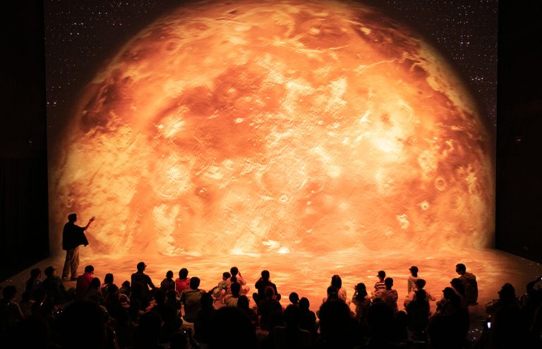 Ihmisryhmää istumassa ja katselemassa immersiivistä esitystä.