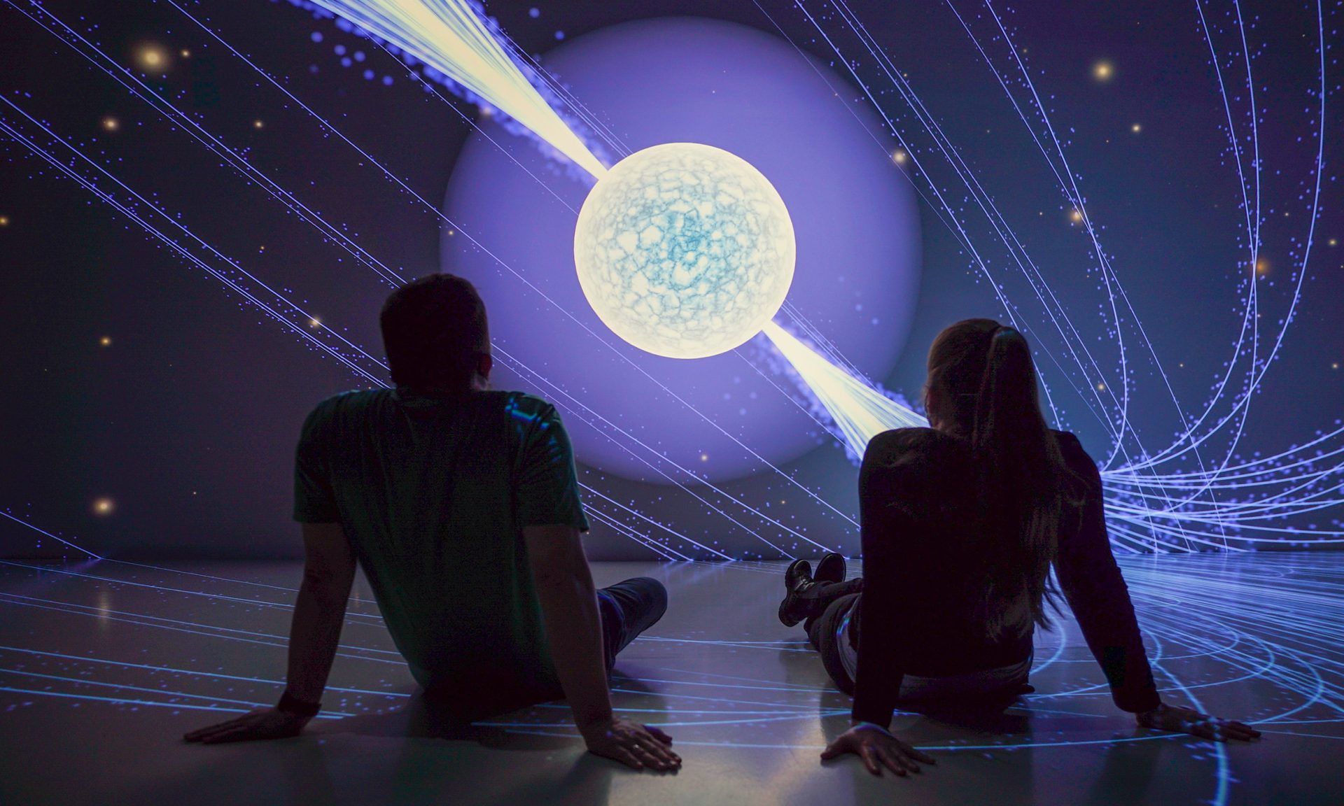 Kaksi henkilöä istumassa ja katsomassa immersiivistä esitystä.